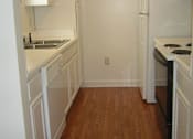 Thumbnail 4 of 6 - A kitchen with white cabinets and a wooden floor.