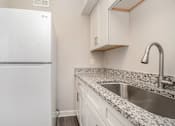 Thumbnail 15 of 23 - A kitchen with a white fridge and a granite counter top.