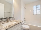 Thumbnail 20 of 23 - A bathroom with a marble countertop and a white toilet.