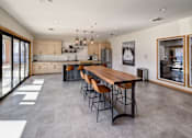 Thumbnail 6 of 23 - A modern kitchen with a long wooden table and chairs.
