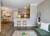 Thumbnail 20 of 47 - A living room with a green couch and a kitchen area in the background.