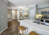 Thumbnail 46 of 47 - A kitchen with a white counter top and wooden stools.