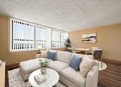 Thumbnail 1 of 20 - A living room with a white couch, a coffee table, and a dining table with chairs.