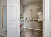 Thumbnail 30 of 47 - A white closet with clothes hanging and shelves.