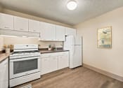 Thumbnail 5 of 20 - A kitchen with white appliances and wooden floors.