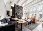 Thumbnail 1 of 38 - A modern living room with a black couch and a stone fireplace.