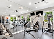 Thumbnail 5 of 40 - A spacious gym with a variety of equipment including treadmills, stationary bikes, and weight machines.