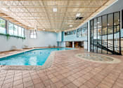 Thumbnail 14 of 20 - A large indoor swimming pool with a tiled floor and a glass wall.