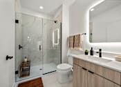 Thumbnail 22 of 46 - A modern bathroom with a glass shower and a white toilet.