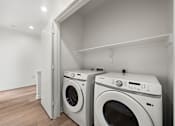 Thumbnail 26 of 46 - Two white front loading washing machines in a laundry room.