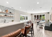Thumbnail 8 of 40 - A modern kitchen with brown leather chairs and a white countertop.