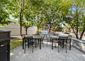Thumbnail 29 of 38 - A patio with a table and chairs surrounded by trees.