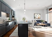 Thumbnail 7 of 32 - A modern kitchen with dark grey cabinets and a black island.