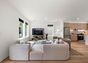 Thumbnail 10 of 46 - A modern living room with a large sectional sofa and a television.