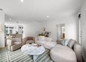 Thumbnail 6 of 46 - A living room with a grey sofa, a white coffee table, and a striped rug.