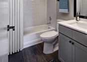 Thumbnail 15 of 23 - A white toilet sits in a bathroom next to a bathtub.