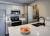 Thumbnail 13 of 23 - A kitchen with a bowl of fruit on the counter.