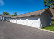 Thumbnail 32 of 37 - a white garage with white doors on the side of a driveway