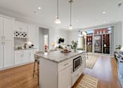 Thumbnail 13 of 32 - A modern kitchen with white cabinets and a marble island.