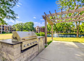 Thumbnail 4 of 24 - A BBQ grill is on a stone base in a sunny park.