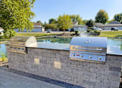 Thumbnail 7 of 21 - A stone wall with two built in BBQs.