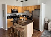Thumbnail 18 of 41 - A kitchen with wooden cabinets and a black refrigerator.
