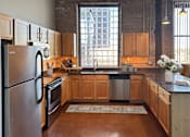 Thumbnail 17 of 41 - A kitchen with wooden cabinets and a large window.