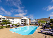 Thumbnail 10 of 37 - A swimming pool surrounded by lounge chairs and apartment buildings.