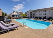 Thumbnail 11 of 37 - A pool surrounded by lounge chairs and apartment buildings.