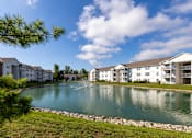 Thumbnail 33 of 37 - A pond in front of apartment buildings on a sunny day.