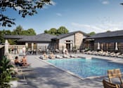 Thumbnail 1 of 7 - Resort-style apartment community pool with lounge chairs, spacious sundeck, and clubhouse exterior surrounded by trees.