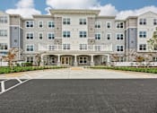 Thumbnail 1 of 36 - A large building with a parking lot in front.