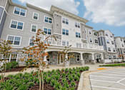 Thumbnail 2 of 36 - Willow Manor at Cabin Branch – Senior 62+ apartment community exterior in Clarksburg, MD with landscaped grounds and modern architecture