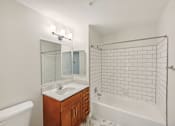 Thumbnail 33 of 36 - A white bathroom with a sink, mirror, and bathtub.
