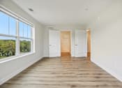 Thumbnail 26 of 36 - A room with white walls and wooden floors with two white doors.