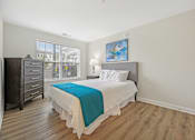Thumbnail 21 of 36 - A bedroom with a bed, nightstand, and dresser.