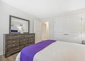 Thumbnail 20 of 36 - A bedroom with a bed, dresser, and mirror.