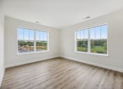 Thumbnail 28 of 36 - A room with two windows overlooking a street and a green field.