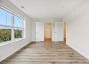 Thumbnail 23 of 36 - A room with white walls and wooden flooring with two white doors.