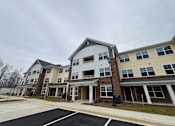 Thumbnail 21 of 75 - Apartment complex with a parking lot in front.