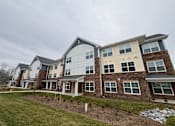 Thumbnail 20 of 75 - A large, multi-story residential building with a mix of brick and siding exteriors.