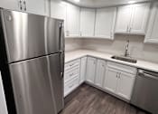 Thumbnail 12 of 29 - A kitchen with a stainless steel refrigerator and white cabinets.