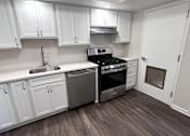 Thumbnail 13 of 29 - A kitchen with white cabinets and a stainless steel stove.