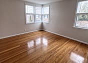 Thumbnail 21 of 29 - A room with wooden floors and two windows letting in natural light.
