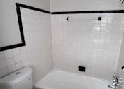 Thumbnail 24 of 29 - A white toilet sits next to a white bathtub in a bathroom.