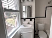Thumbnail 23 of 29 - A white bathroom with a sink, toilet and window.