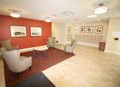 Thumbnail 7 of 9 - A waiting room with chairs and pictures on the wall.