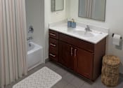 Thumbnail 4 of 9 - A bathroom with a white sink and a brown cabinet.