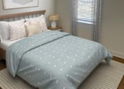 Thumbnail 3 of 9 - A bed with a blue comforter with white dots is in the foreground of a room with a window and a picture on the wall.