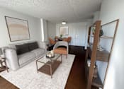 Thumbnail 1 of 26 - A living room with a grey couch, a brown coffee table, and a painting on the wall.